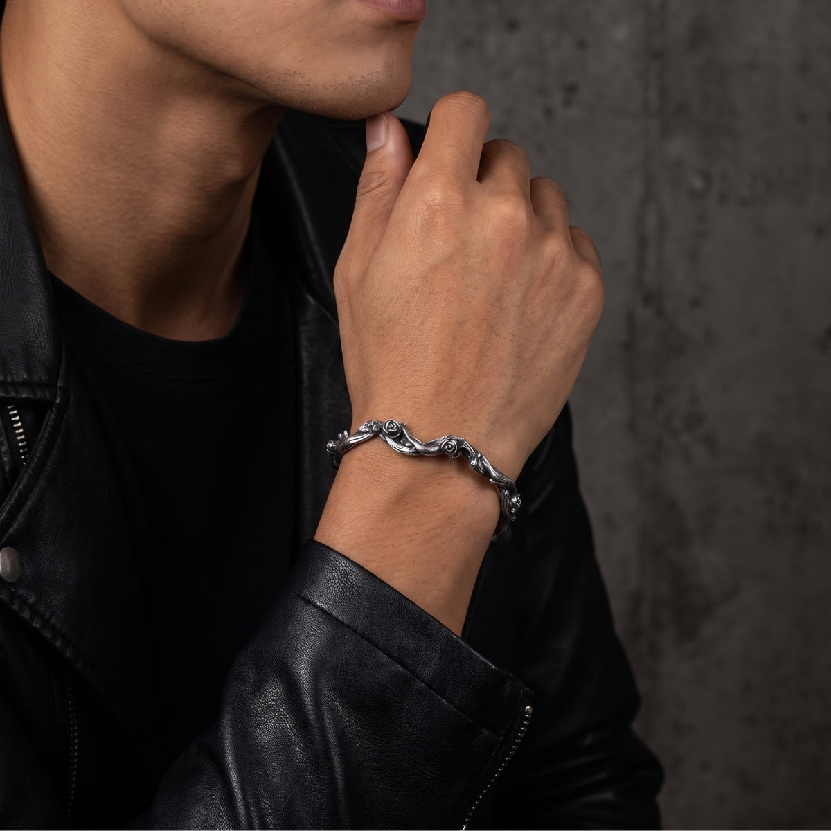 Oxidized silver rose vine cuff bracelet worn on a wrist with a black leather jacket.