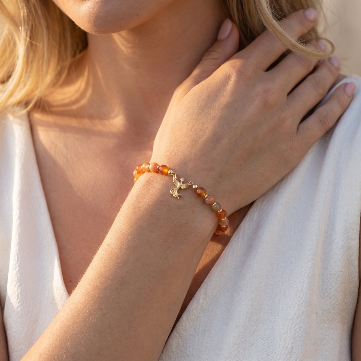 Phoenix charm bracelet with orange and honey-tone beads worn on a wrist