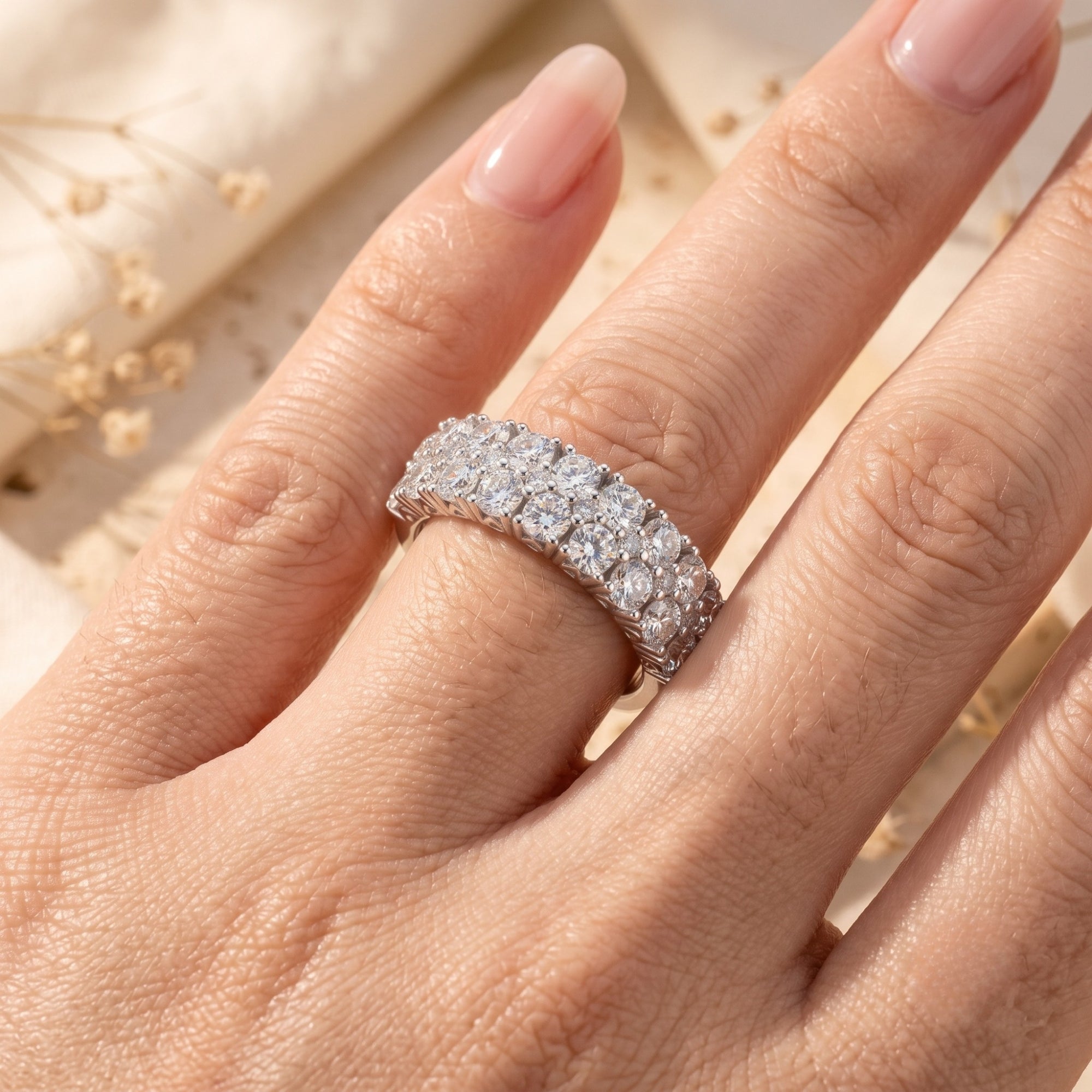 Triple row sterling silver promise ring with round cubic zirconia worn on a model's finger.