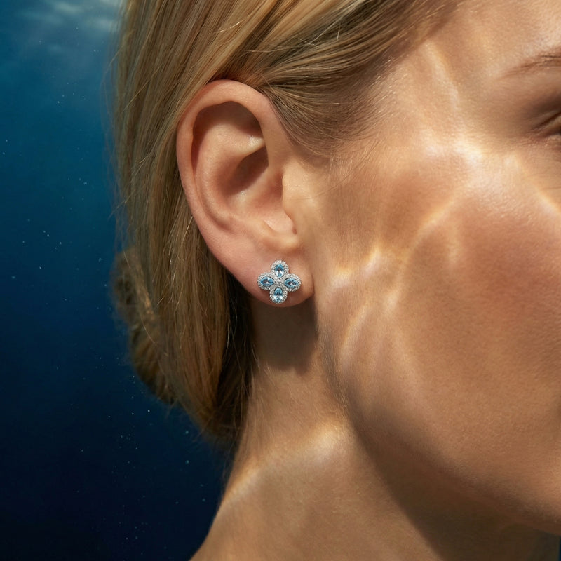 Woman wearing a silver floret cluster earring with pear cut aquamarine stones, shown in a side profile view.