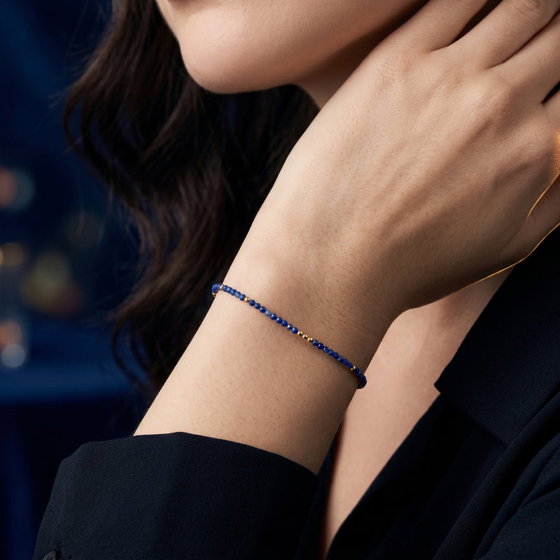 Dainty natural lapis lazuli bead bracelet with gold accents worn on a woman's wrist.