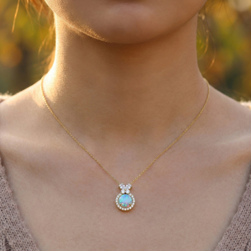 Model wearing the gold vermeil Orianne necklace featuring a round blue opal pendant with a crystal halo.