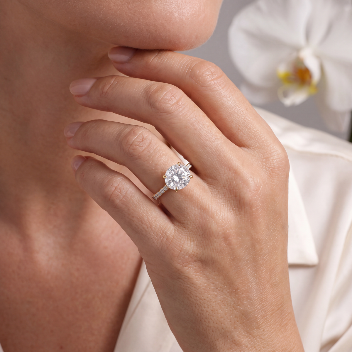 Yellow gold east-west oval moissanite engagement ring worn on a model's hand.