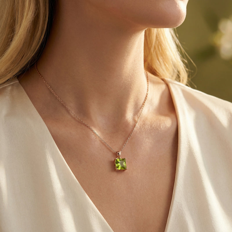 Model wearing the princess cut natural peridot necklace in 18K rose gold vermeil against a cream silk blouse.