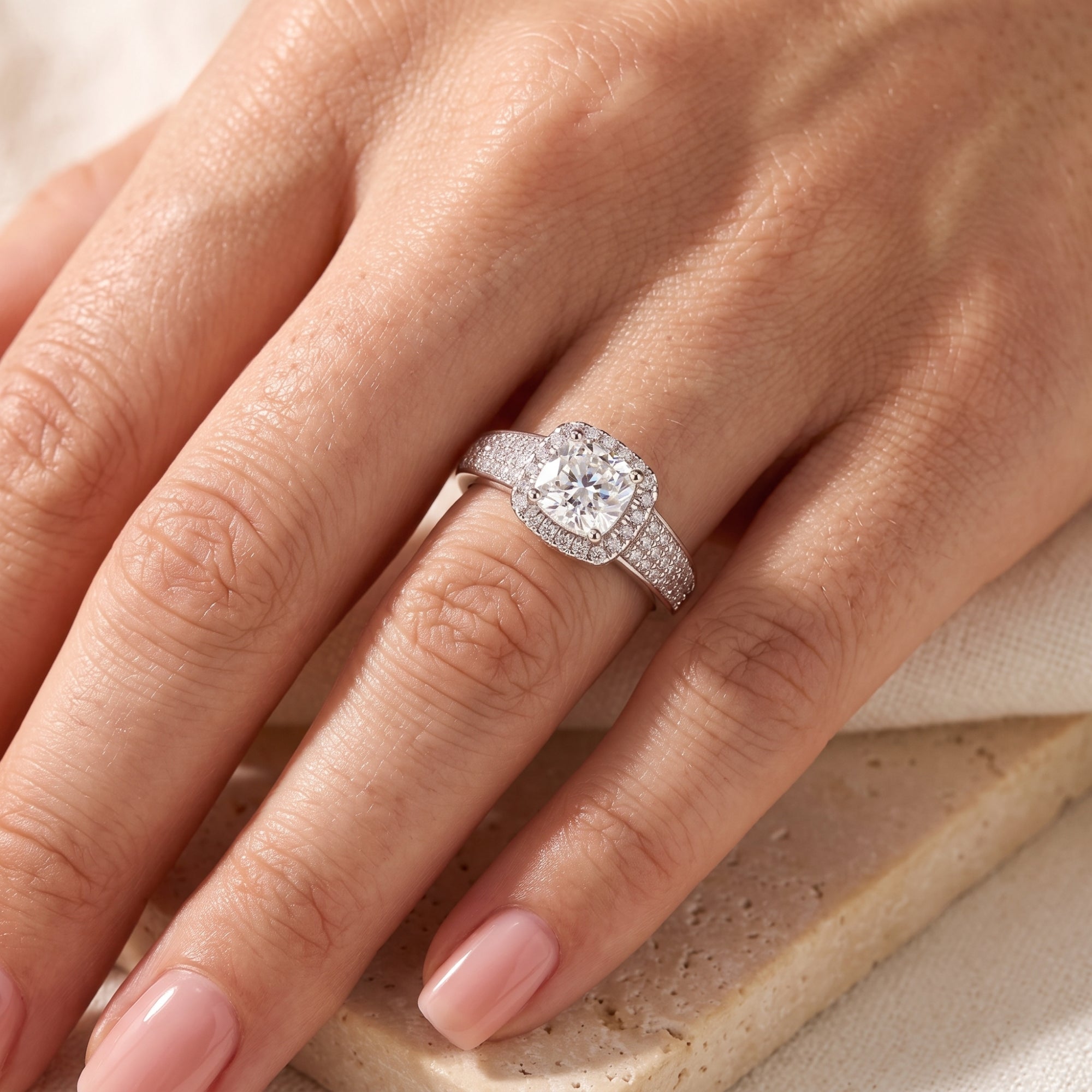Aria silver cushion halo ring worn on a woman's hand.