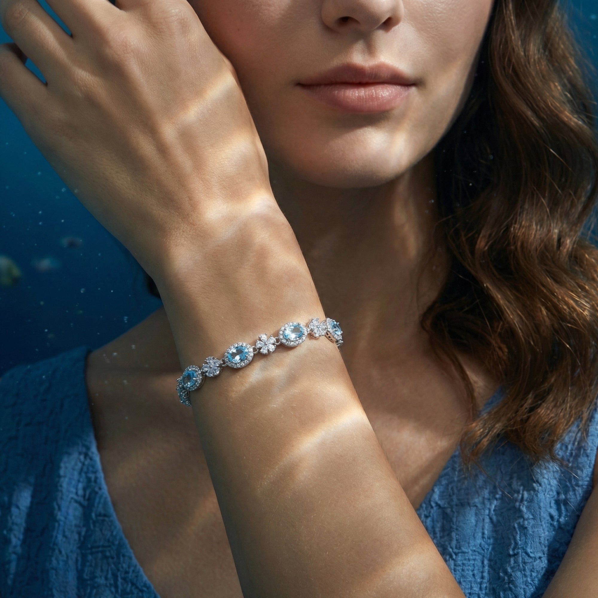 Women's white gold bracelet with oval aquamarine stones and flower accents worn on a model's wrist.