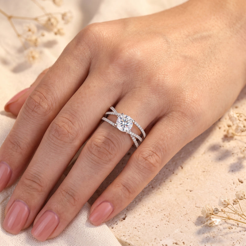 Silver criss-cross solitaire ring with round cut stone worn on a woman's hand.