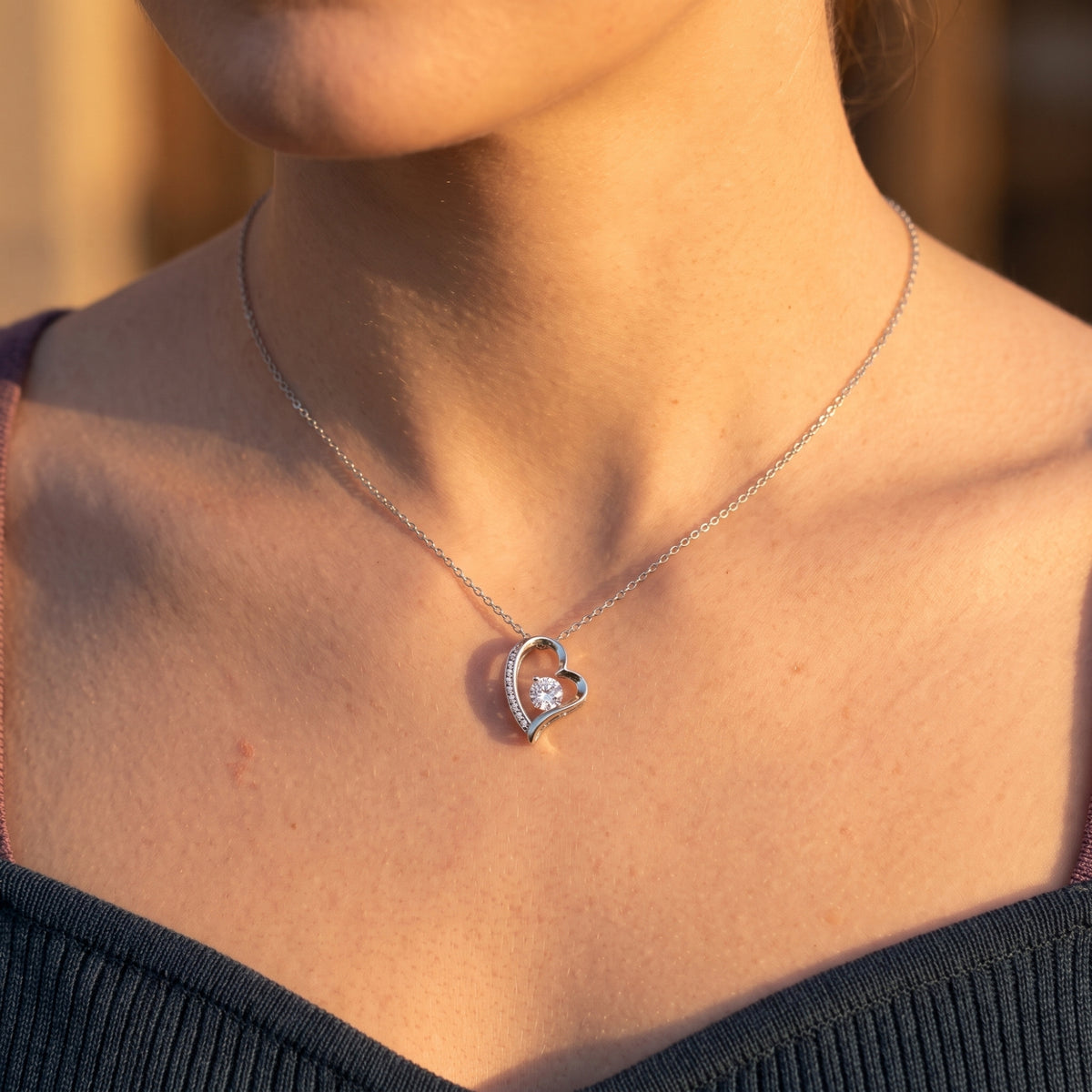 Silver-finish asymmetric heart necklace worn at the neckline.