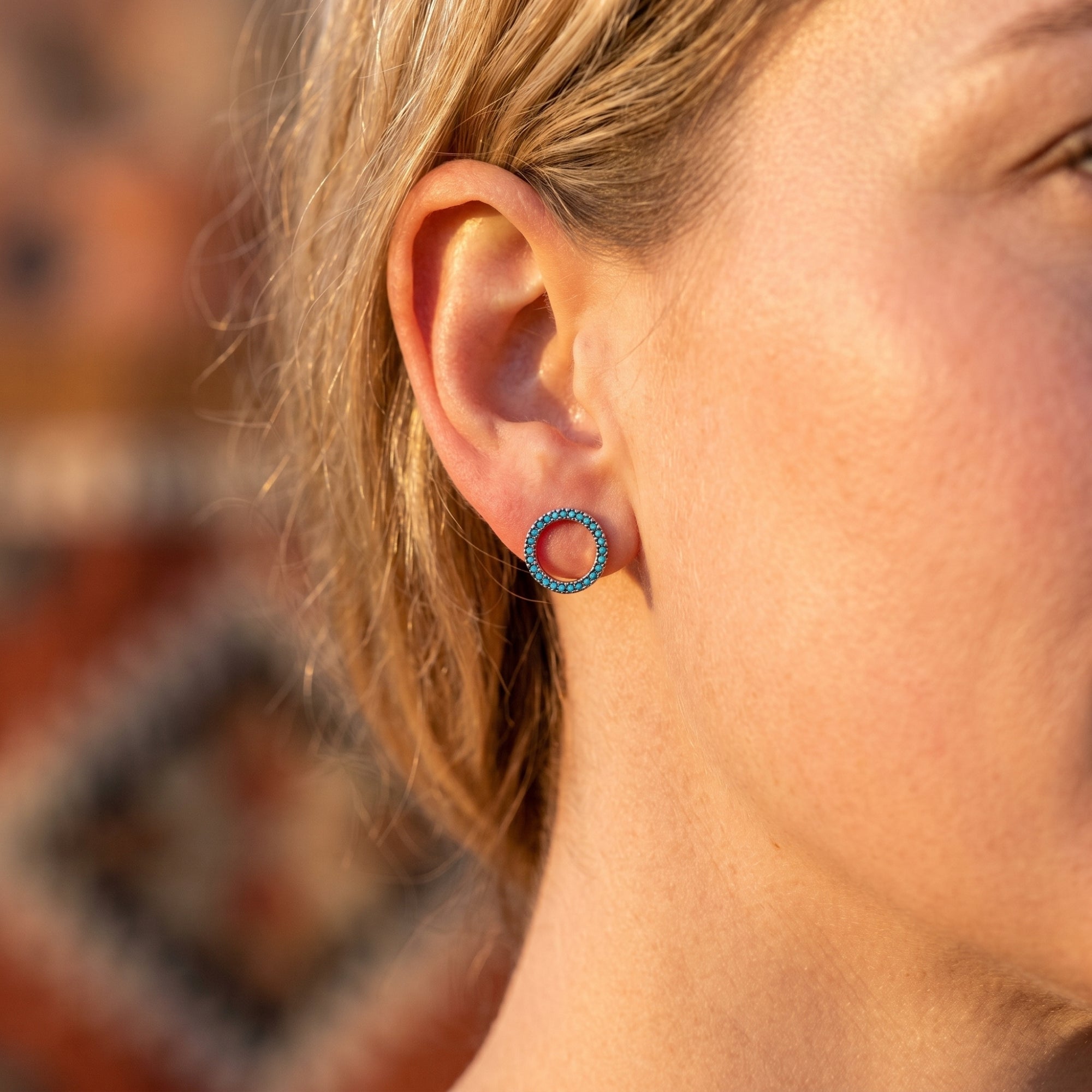 Woman wearing a silver turquoise circle earring from the Santa Fe collection on her ear.