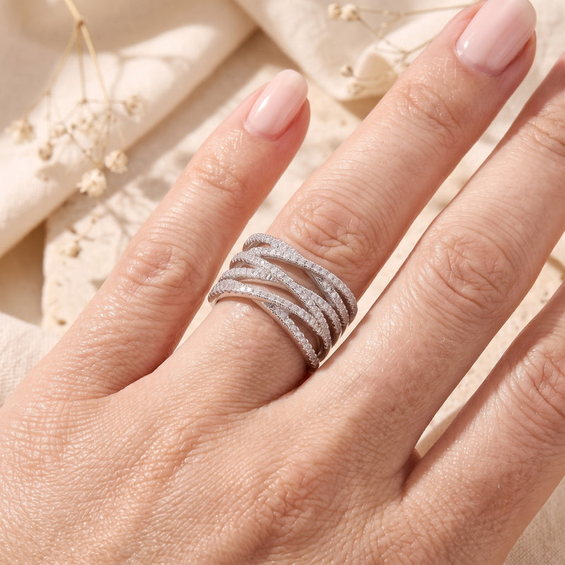 Silver Nexus crossover ring with micro-pavé simulated diamonds worn on a model's finger.