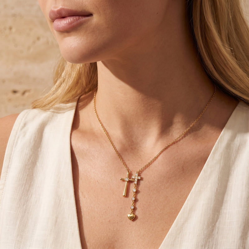 Model wearing the gold double cross lariat necklace with a deep V-neck white top.