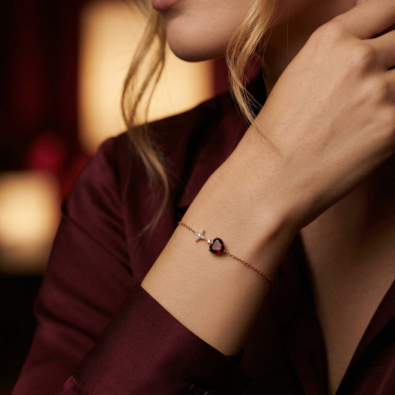 The Amira heart bracelet in 18K rose gold with a natural garnet worn on a woman's wrist.