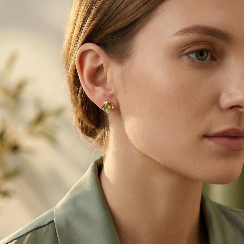 Woman wearing a gold vermeil Yvaine stud earring featuring a vibrant oval cut green peridot.