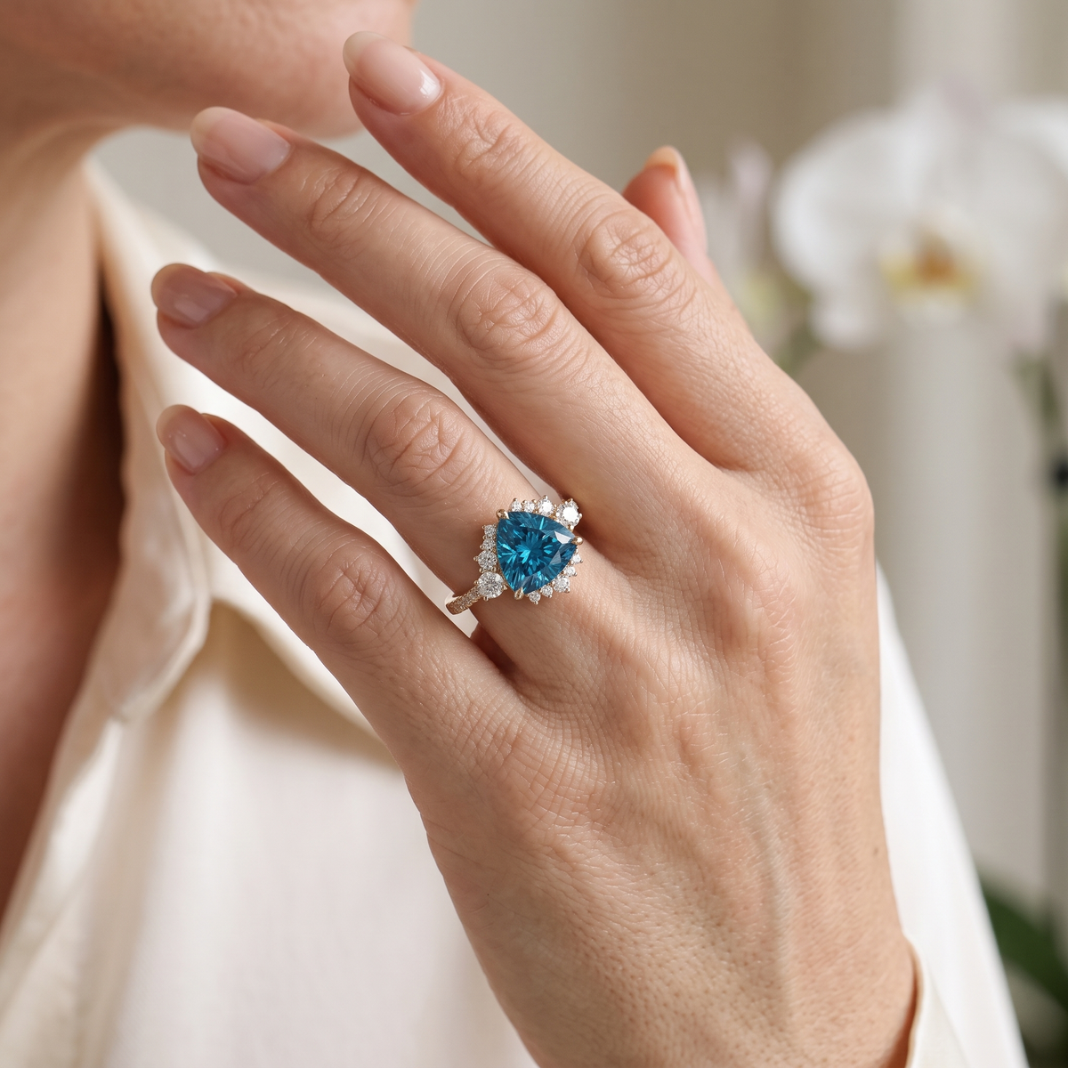 A model wearing a yellow gold trillion-cut blue moissanite cluster halo ring on her finger.