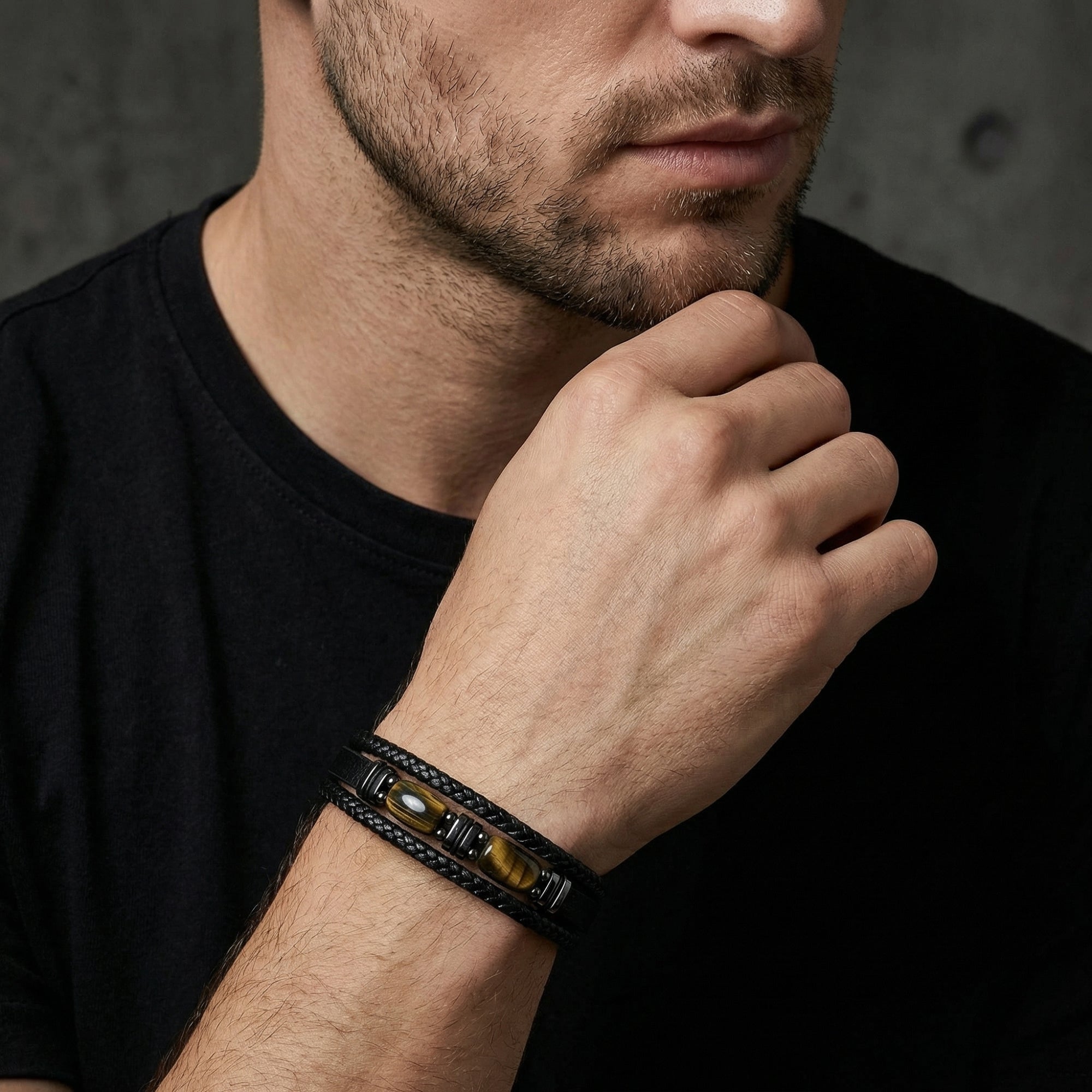 Men's black leather Crucible bracelet with tiger's eye stones and black stainless steel worn on a wrist.
