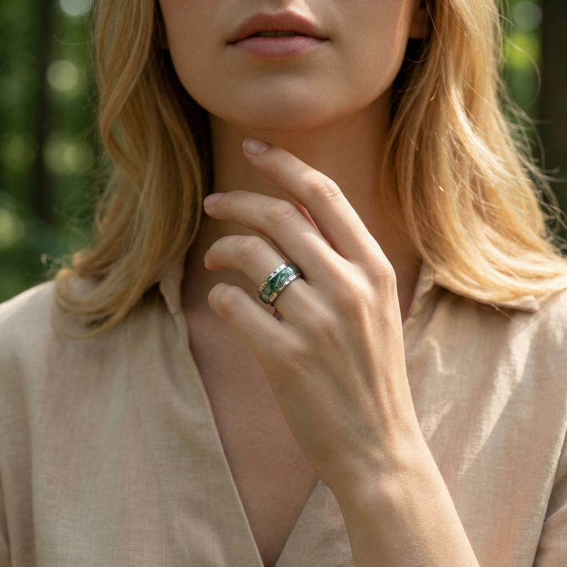 Woman wearing the natural moss agate sterling silver inlay band ring on her finger in a natural setting.