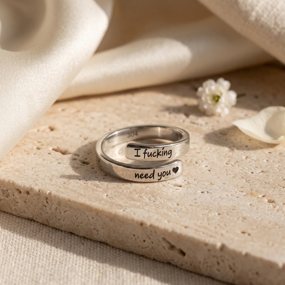 Close-up of silver wrap ring engraved I fucking need you with a heart