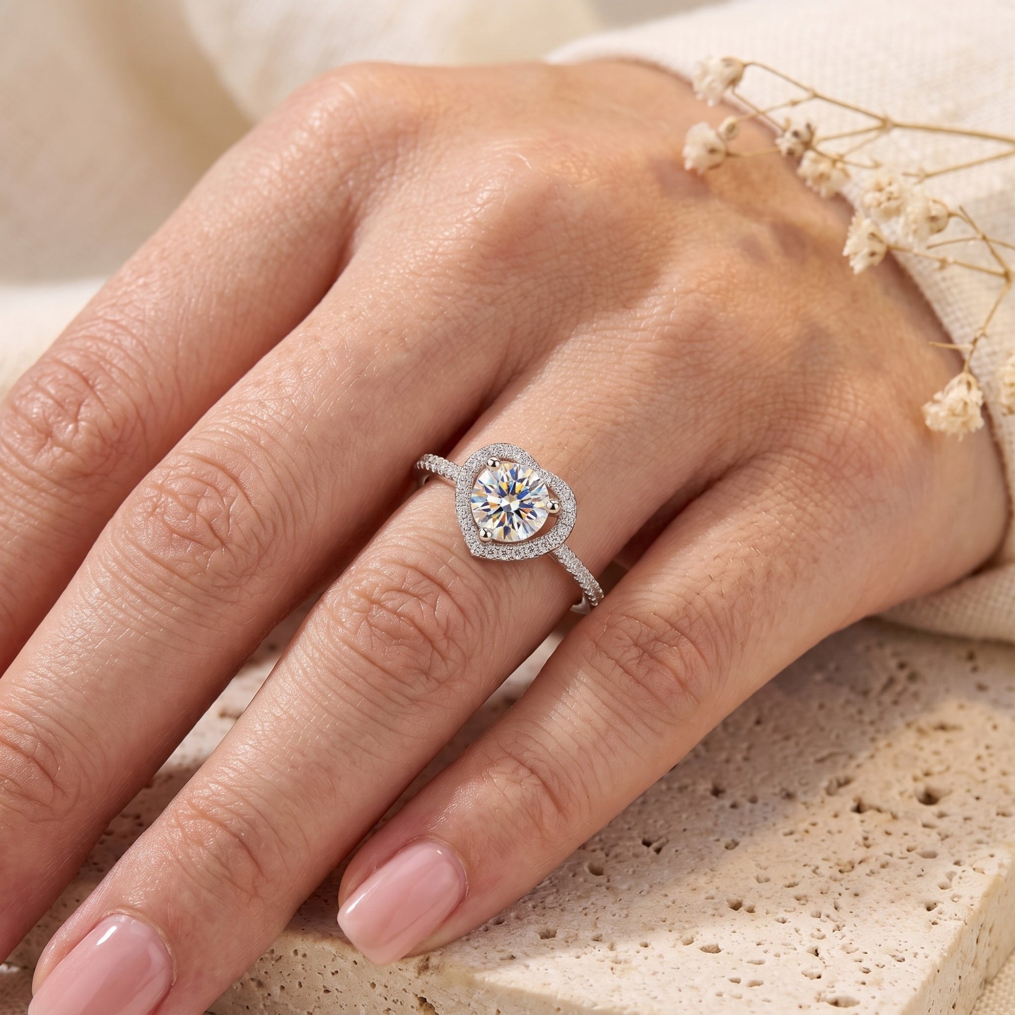 Sterling silver heart halo promise ring with round center stone worn on a woman's hand.