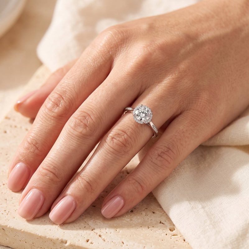 Round cubic zirconia silver halo ring worn on a woman's hand.