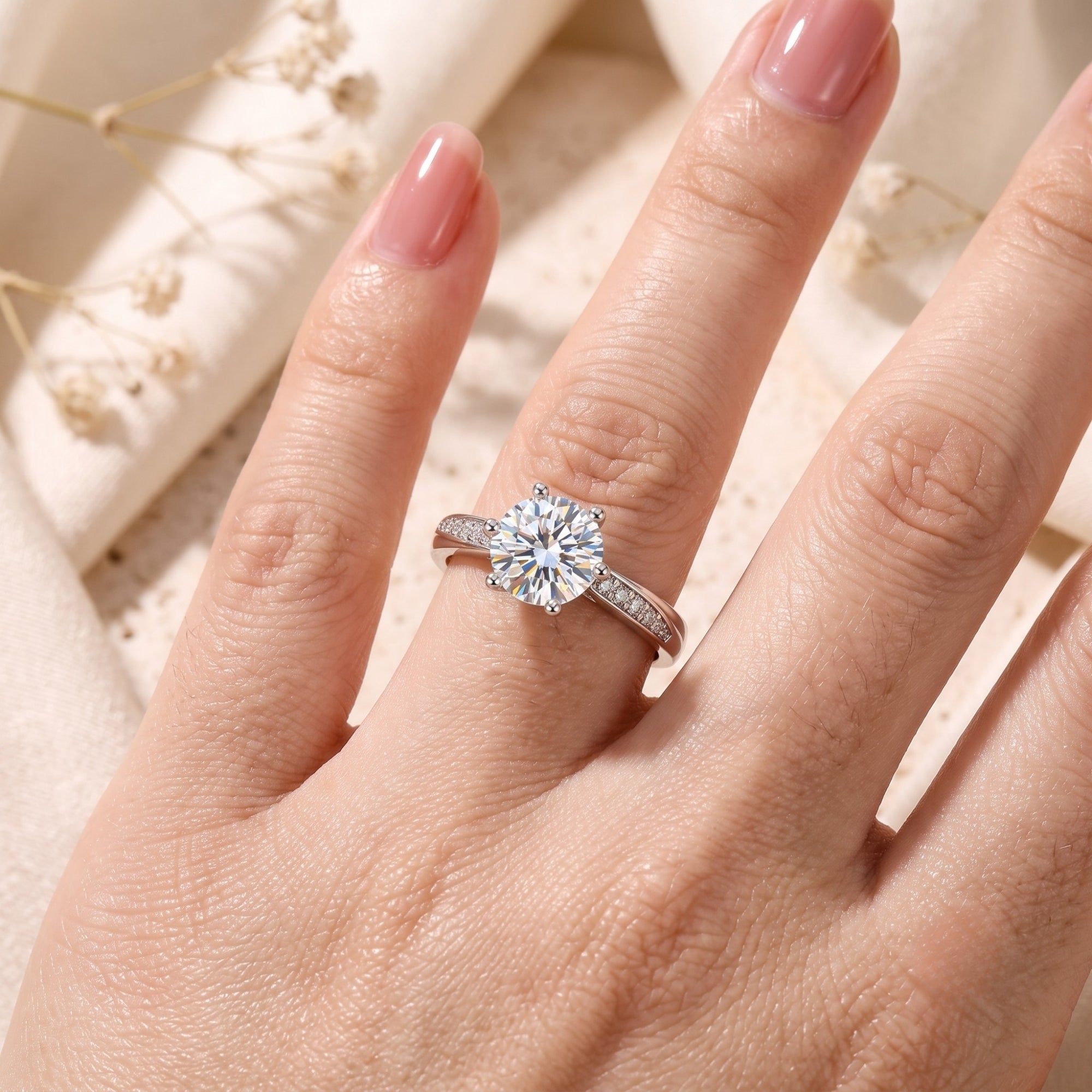 Round cut silver promise ring worn on a finger with pavé accents.