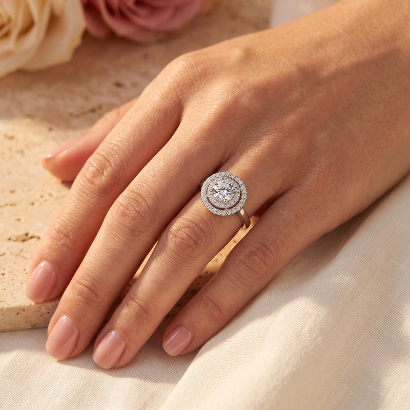 Women's S925 sterling silver double halo ring with round simulated diamond worn on a finger.