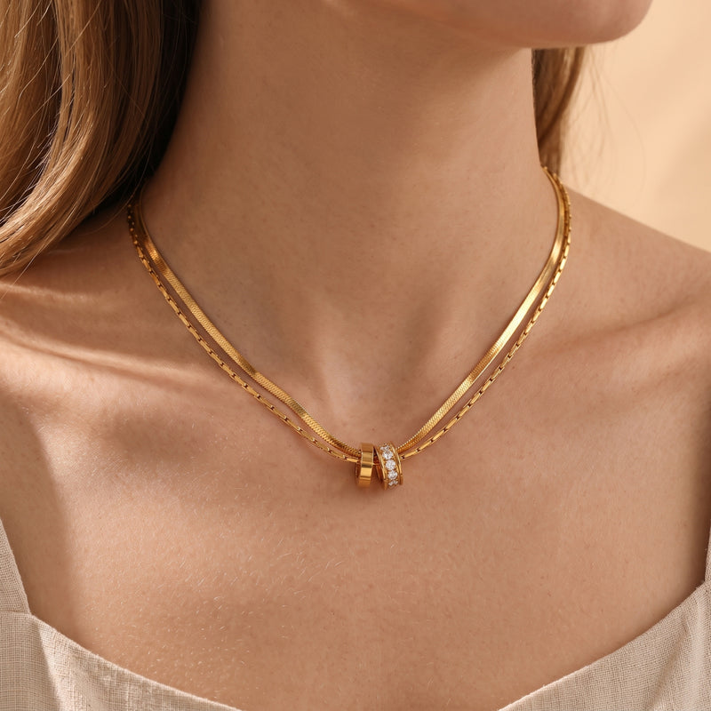 18K gold layered necklace with interlocking CZ rings shown on a model's neck.
