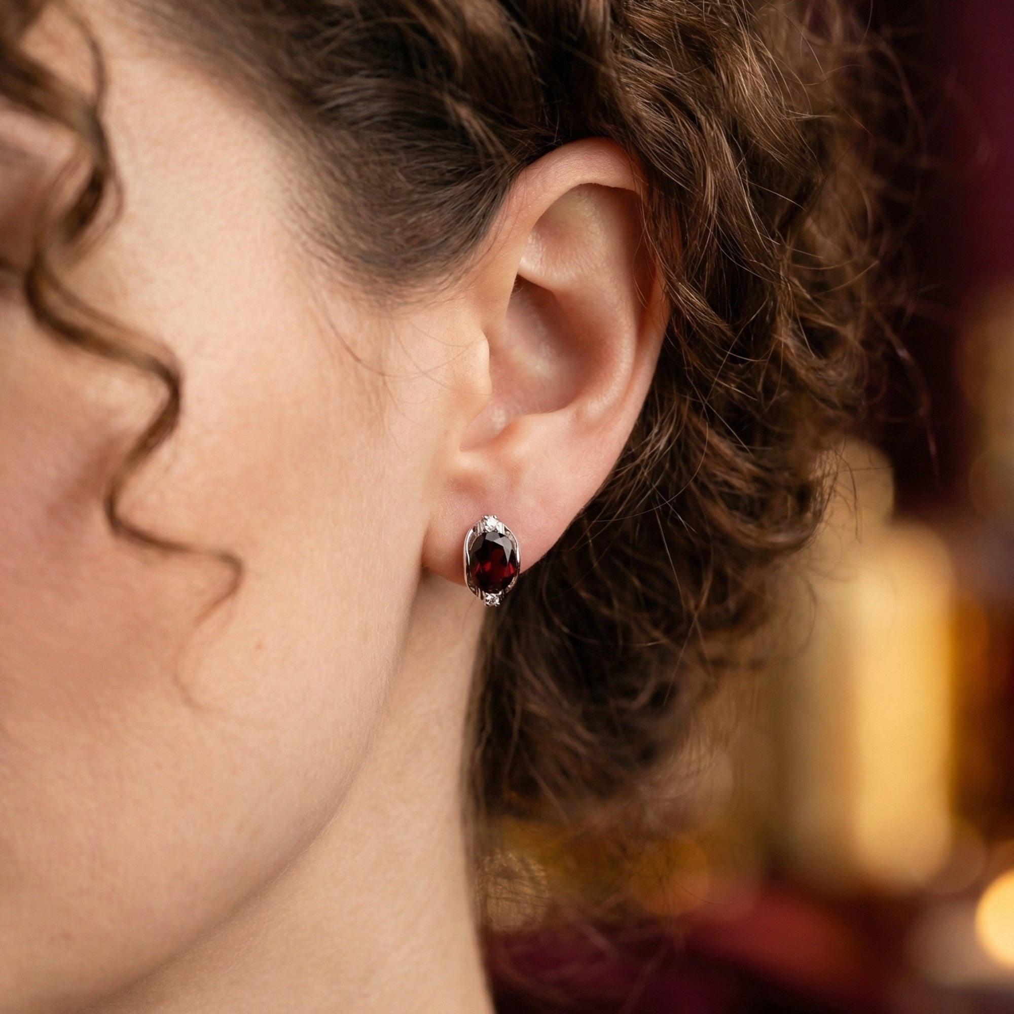 Close-up of a woman wearing the Alessia sterling silver drop earring with a large 8x10mm oval cut garnet.