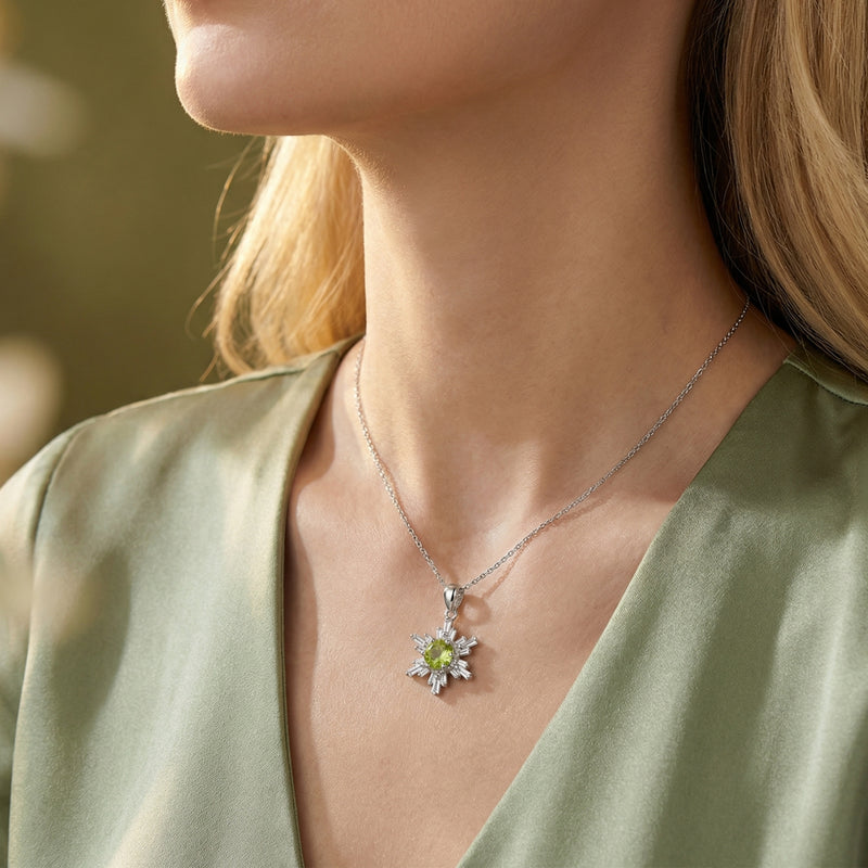 Woman wearing the Elina natural peridot snowflake pendant in S925 sterling silver with a green silk blouse.