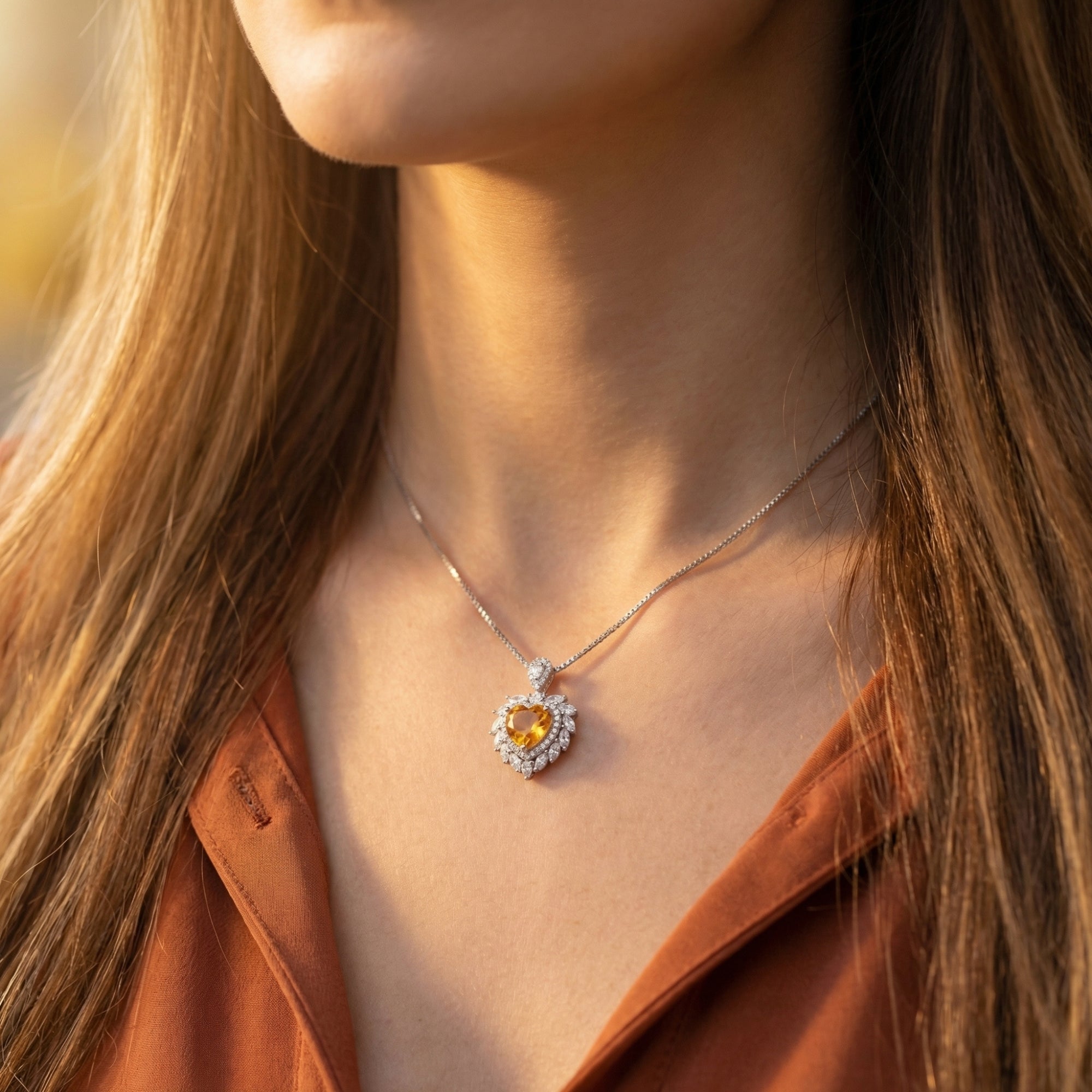 Heart cut citrine necklace in sterling silver worn by a woman against a warm, sunlit background.