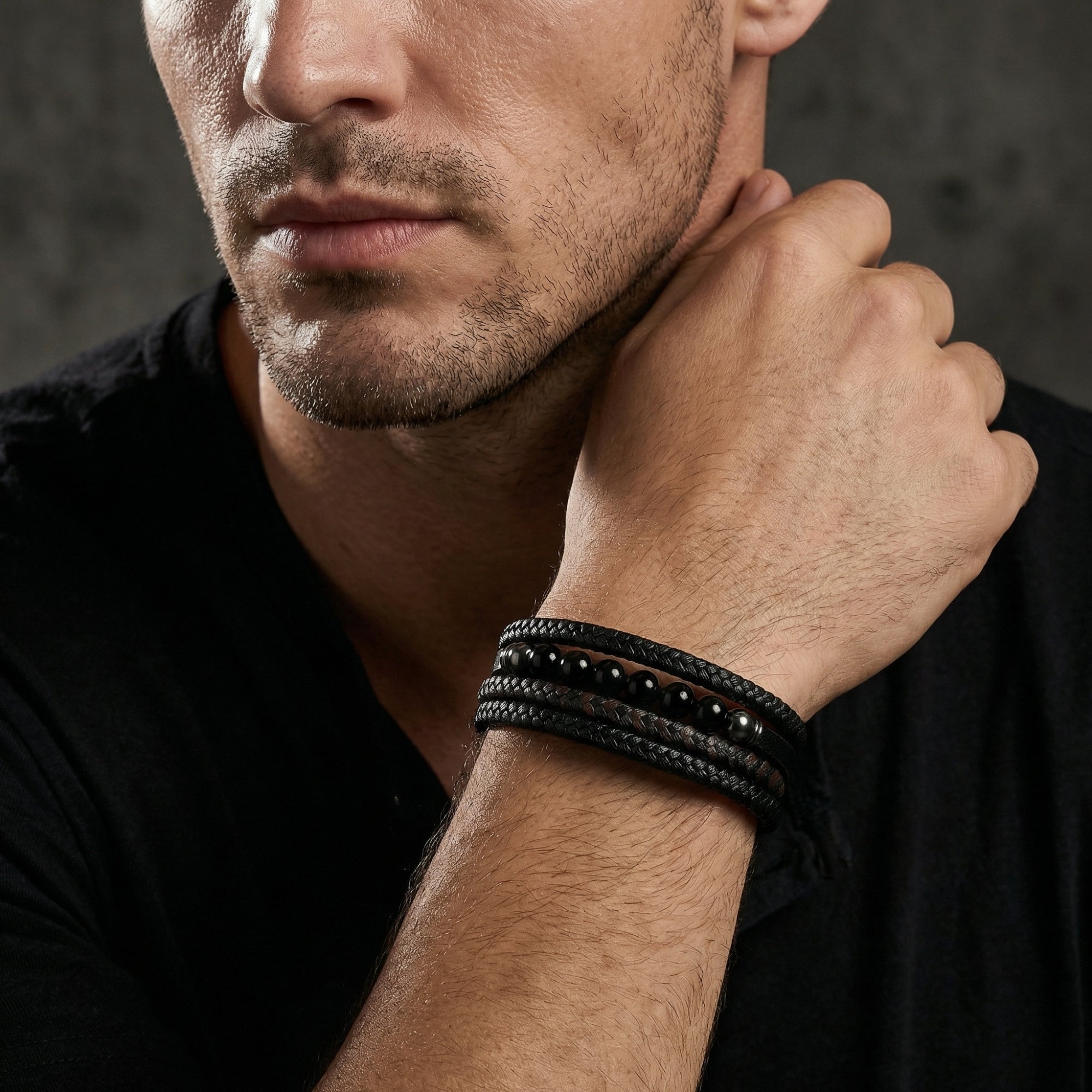 The Valor Bracelet worn on a man's wrist, featuring multi-strand black and brown braided leather with black beads.