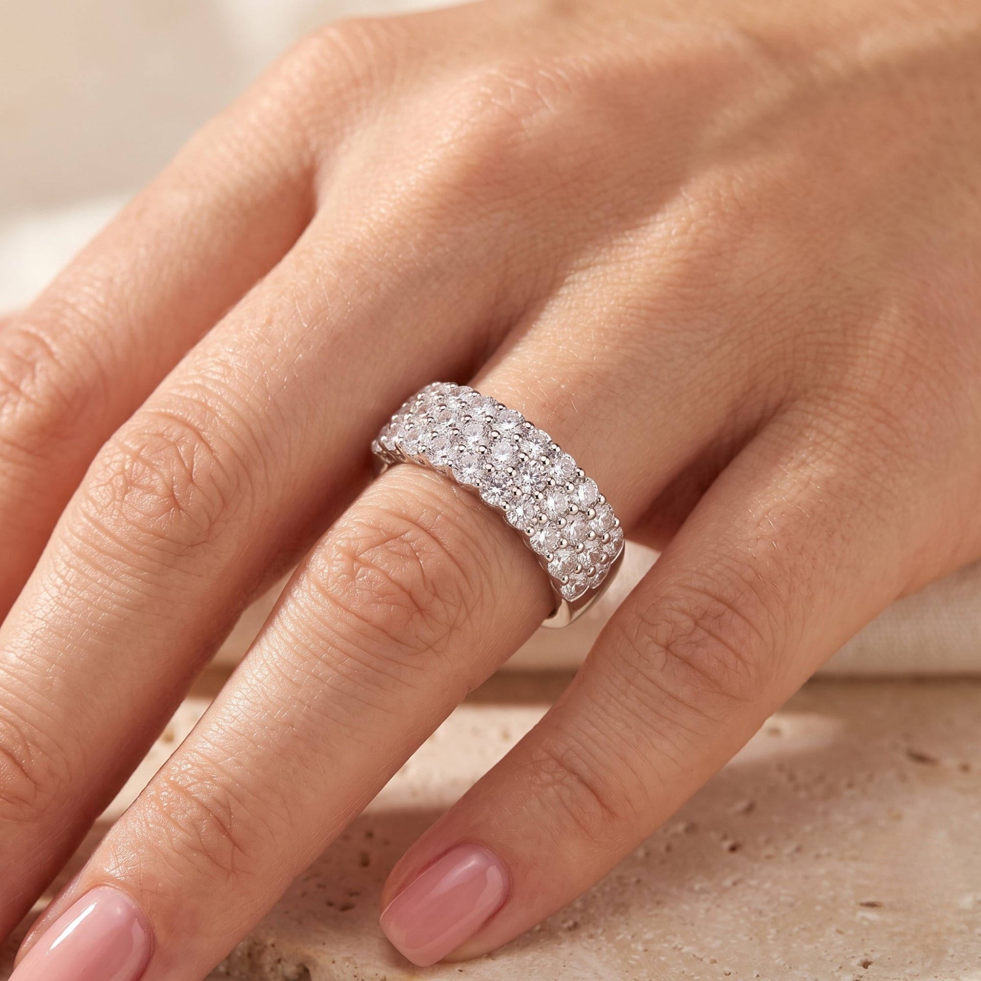Multi-row sterling silver pavé ring with round simulated diamonds worn on a finger.