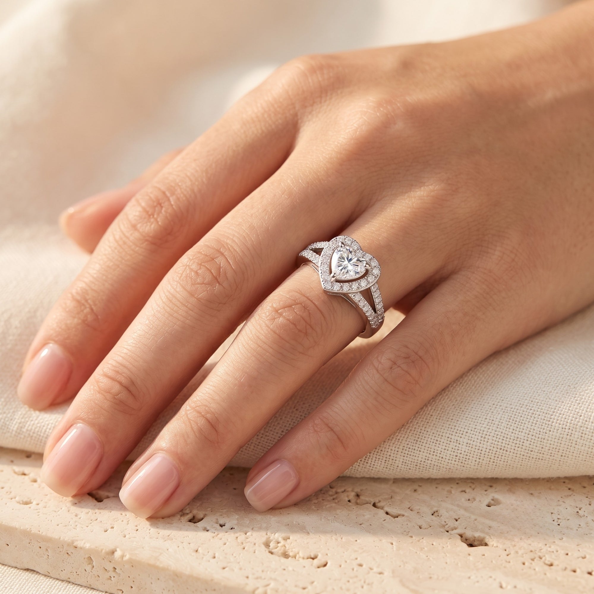 Sterling silver heart halo promise ring with cubic zirconia worn on a hand.