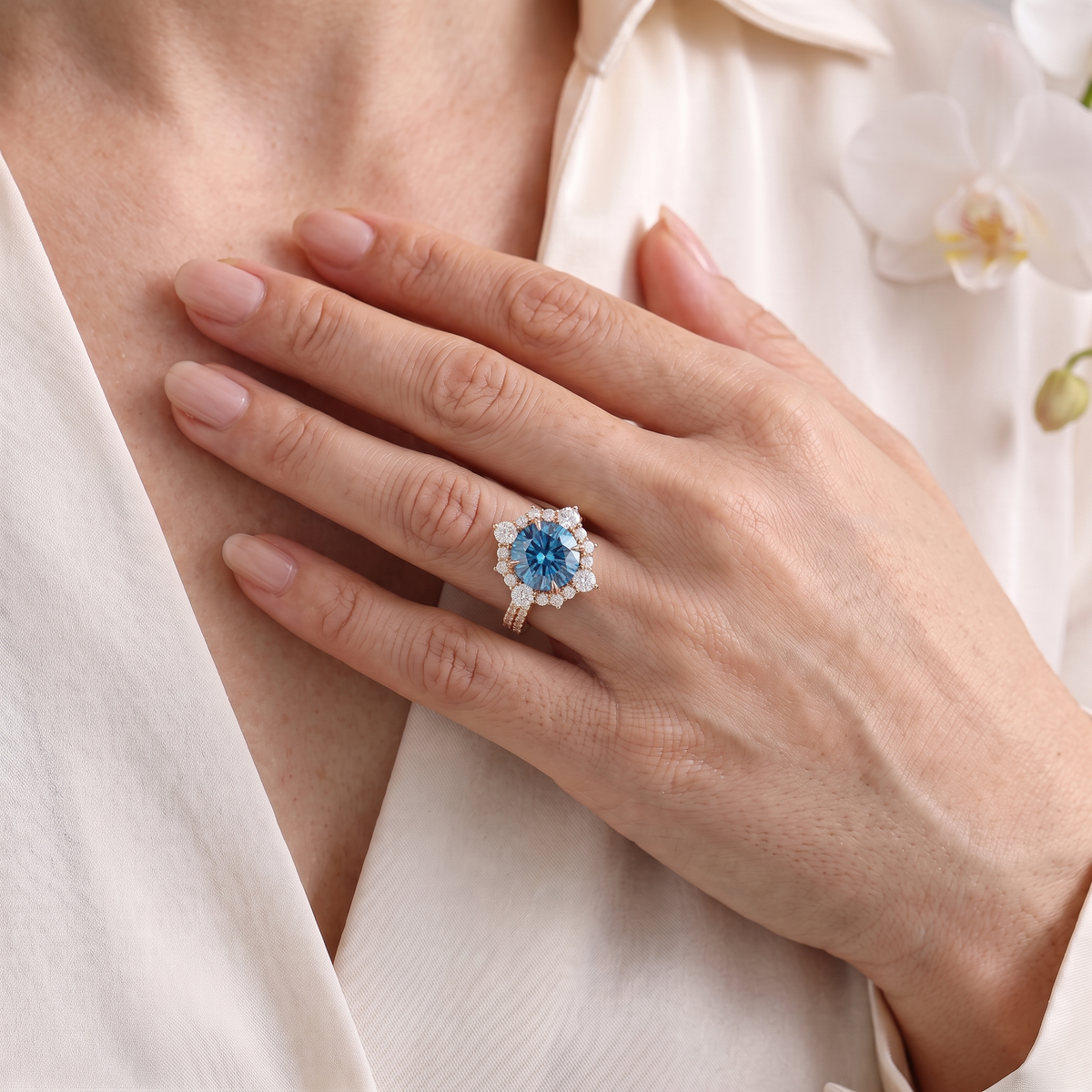 Rose gold round blue moissanite halo engagement ring worn on a woman's hand.