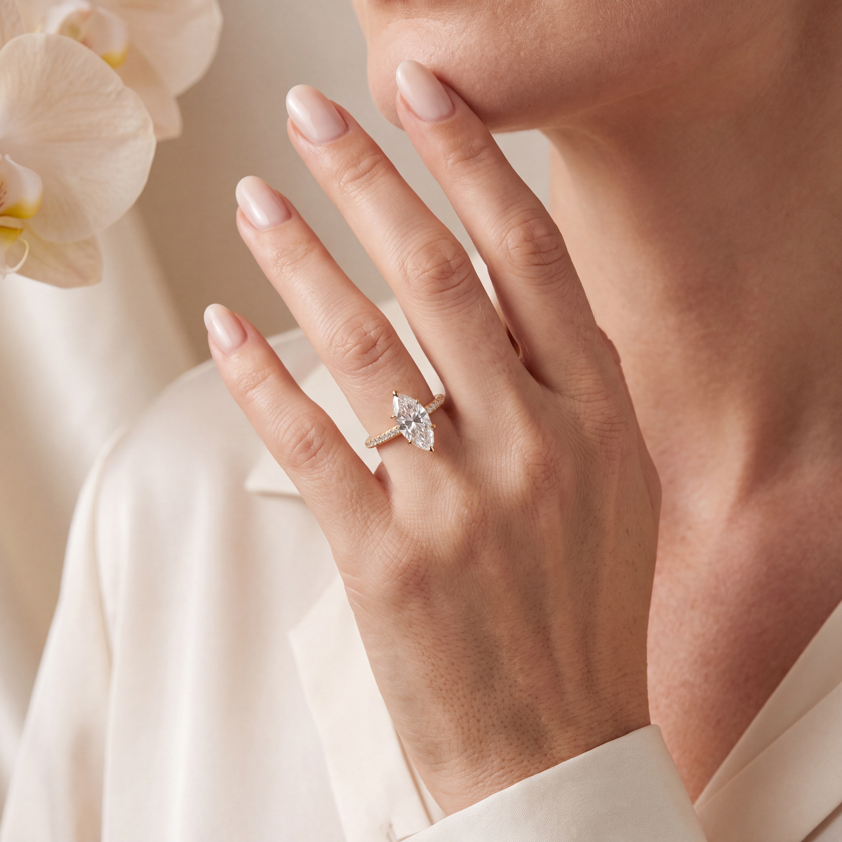 Close-up of a model wearing a yellow gold marquise moissanite engagement ring on her finger.