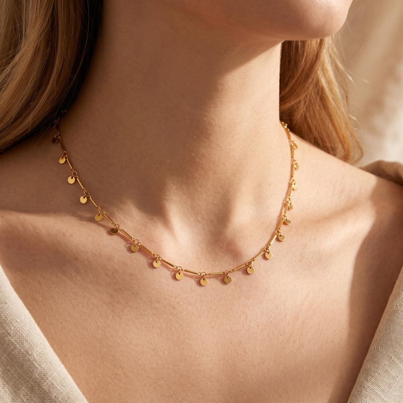 Gold-plated disc necklace worn on a woman's neck.