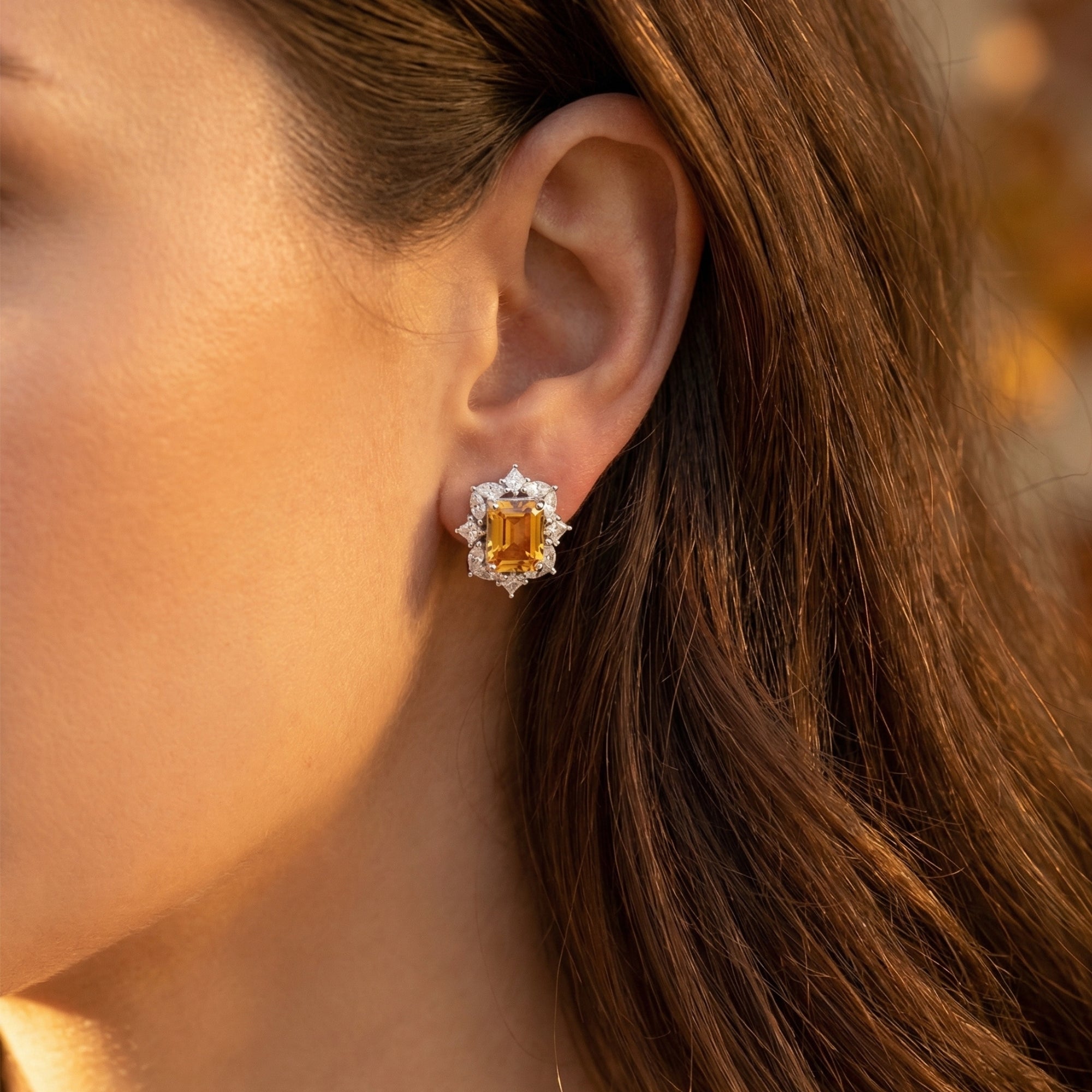 Model wearing an emerald cut natural citrine stud earring with a diamond halo in white gold.