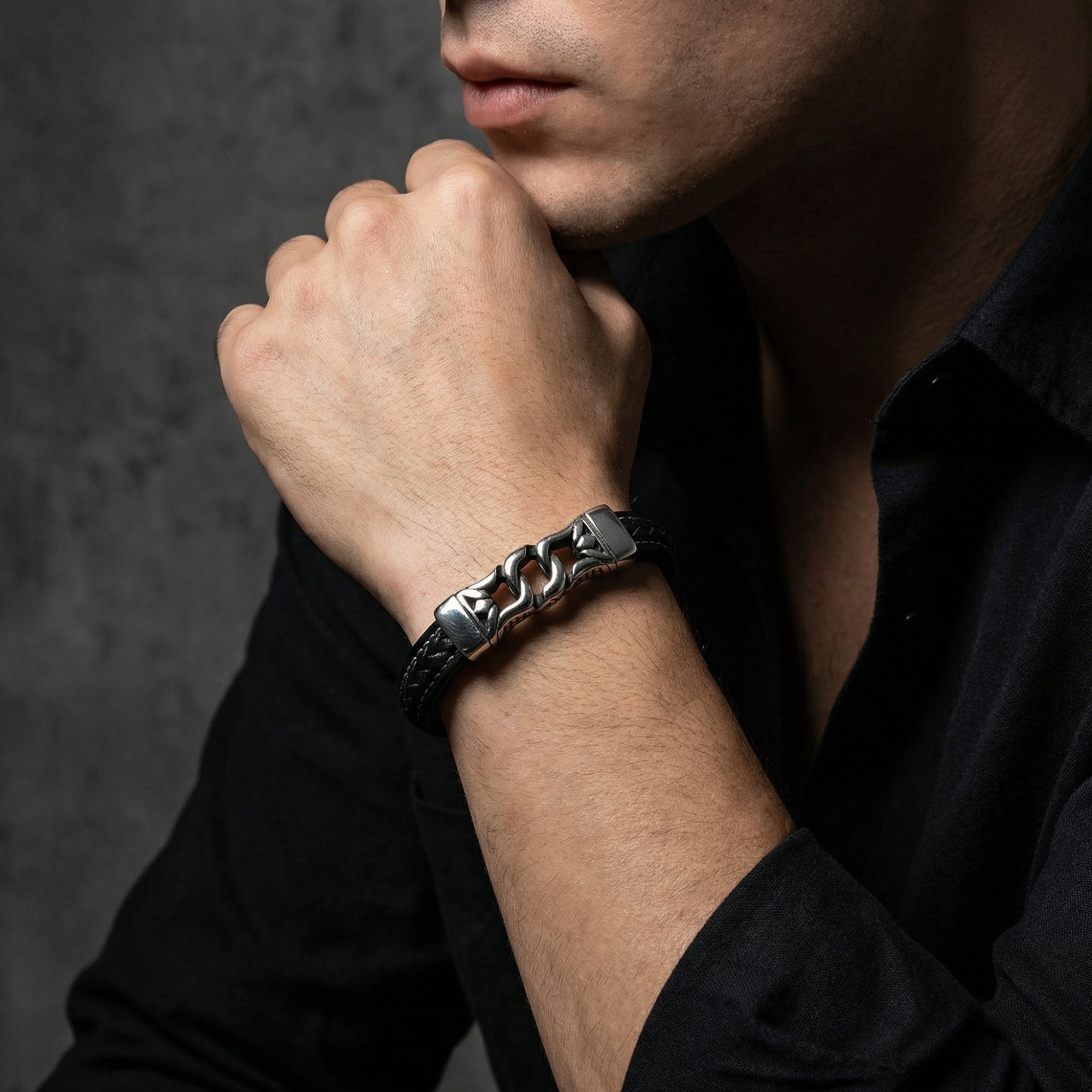 Men's Nexus Bracelet in black leather and silver stainless steel worn on a wrist with a black button-down shirt.