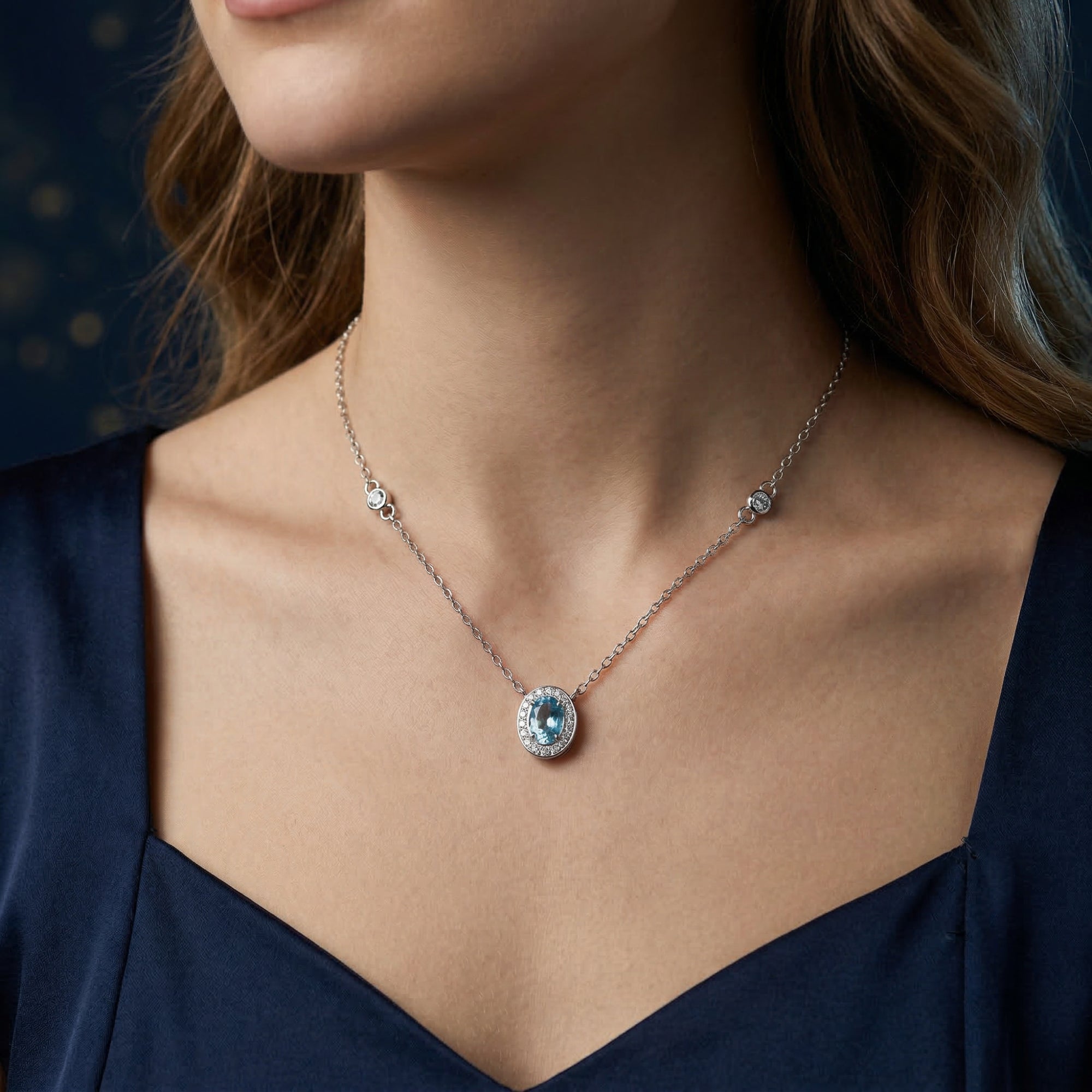 Model wearing the Aquilina oval blue topaz necklace in silver, showing the pendant on the neckline.