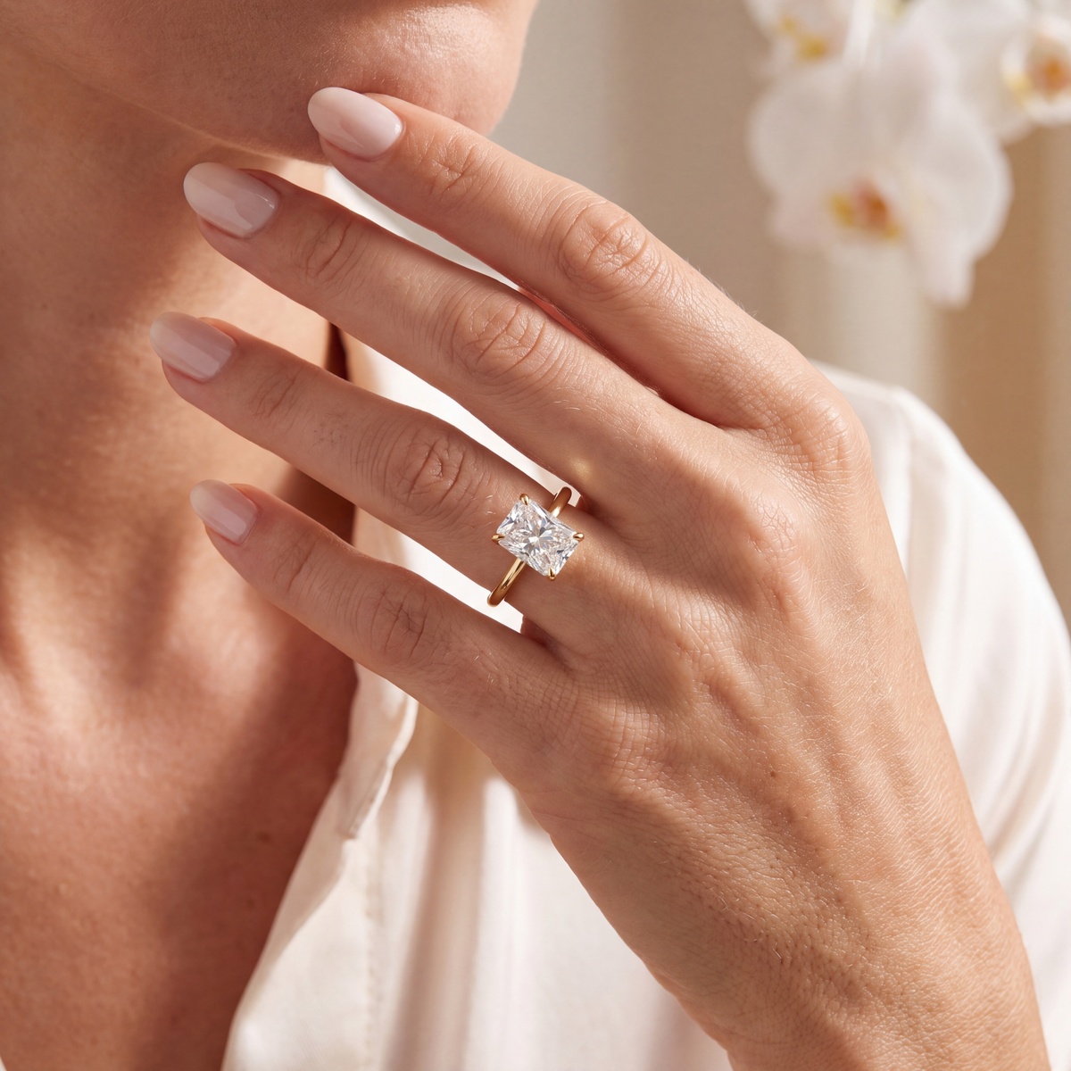 Model wearing a yellow gold radiant-cut moissanite solitaire engagement ring on her hand.