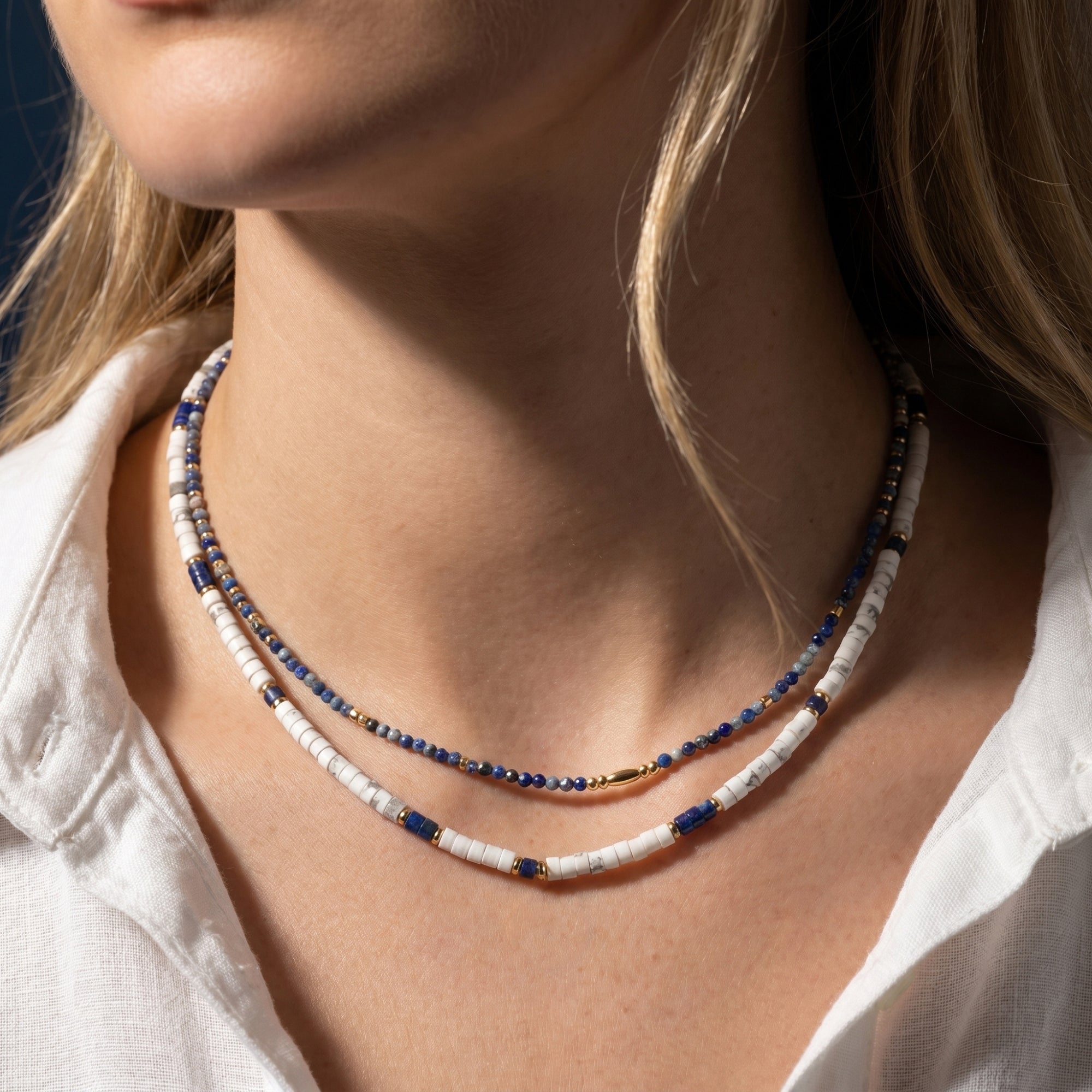 Model wearing the Midnight Horizon layered necklace set with blue lapis and white beads in yellow gold plating.
