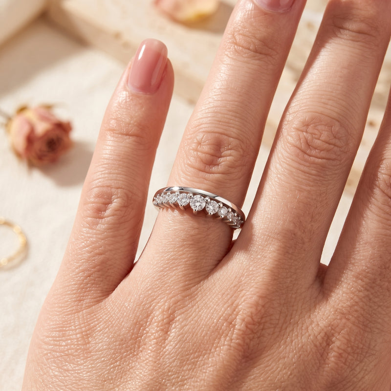 Silver curved promise ring with graduated cubic zirconia worn on a finger.