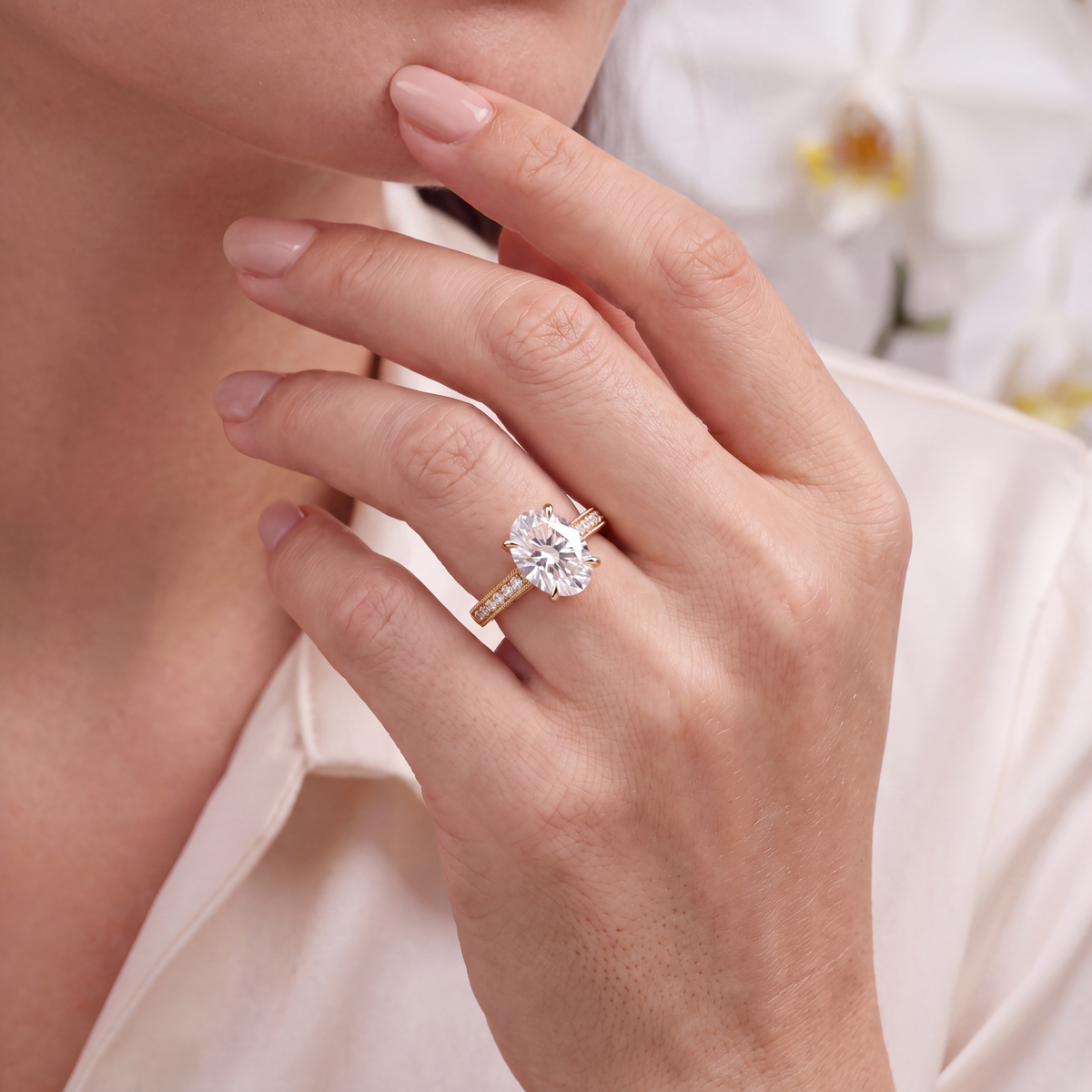 Model wearing a yellow gold oval moissanite engagement ring on her hand.