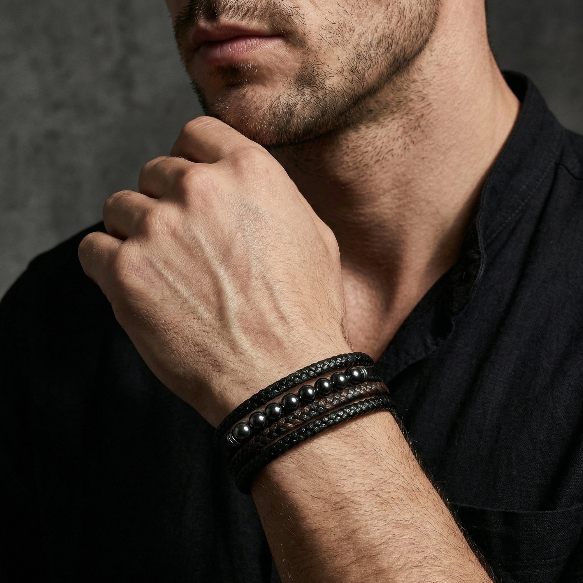 Men's multi-layer leather bracelet with gunmetal beads worn on a wrist, paired with a black linen shirt.