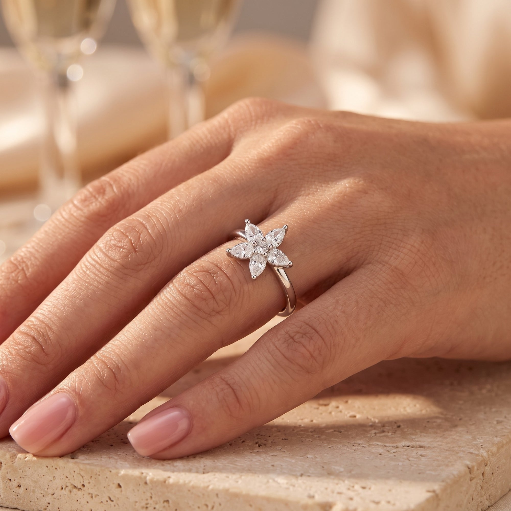 Pear-cut cubic zirconia blossom ring in silver worn on a hand.