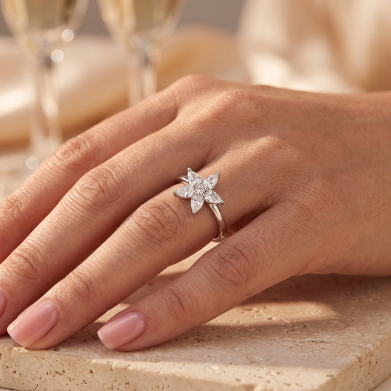 Pear-cut cubic zirconia blossom ring in silver worn on a hand.