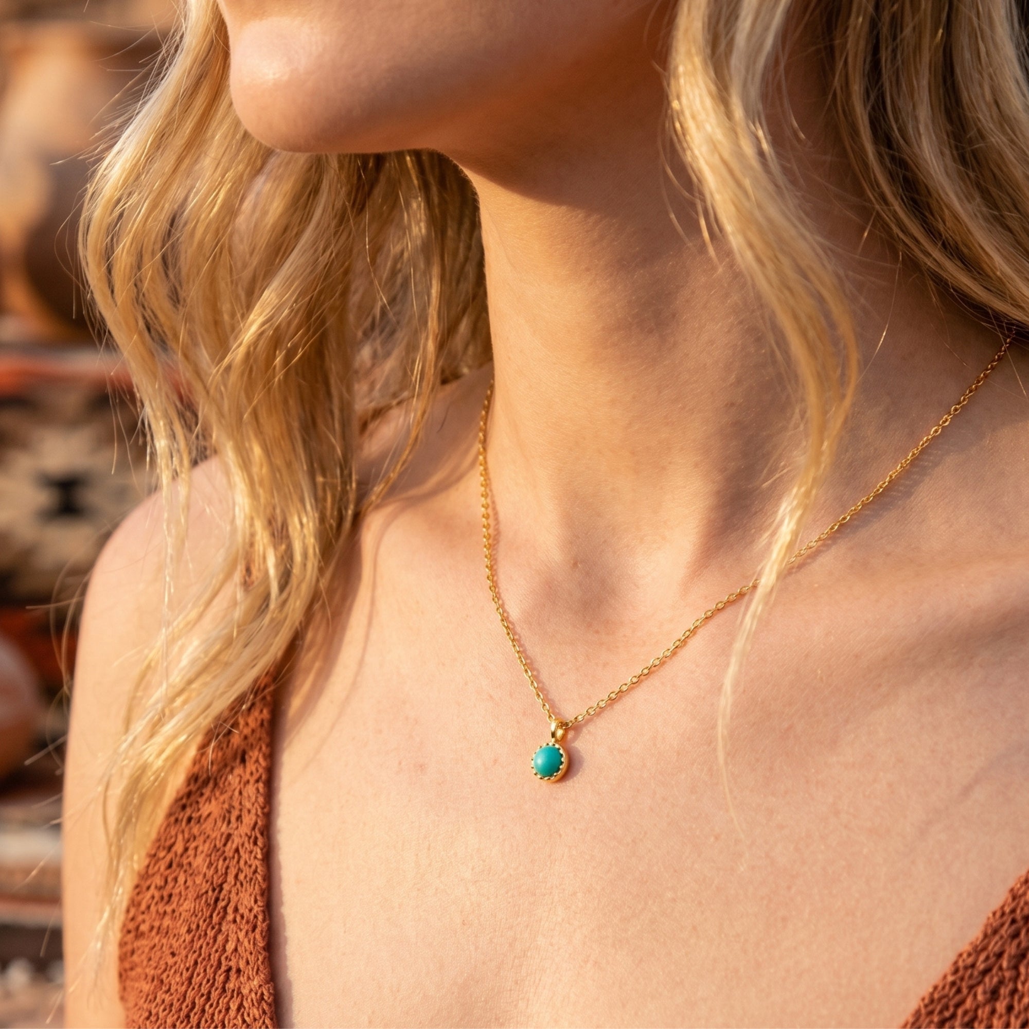 Model wearing the gold vermeil Catalina turquoise necklace with a round cabochon pendant in a warm, sunlit outdoor setting.
