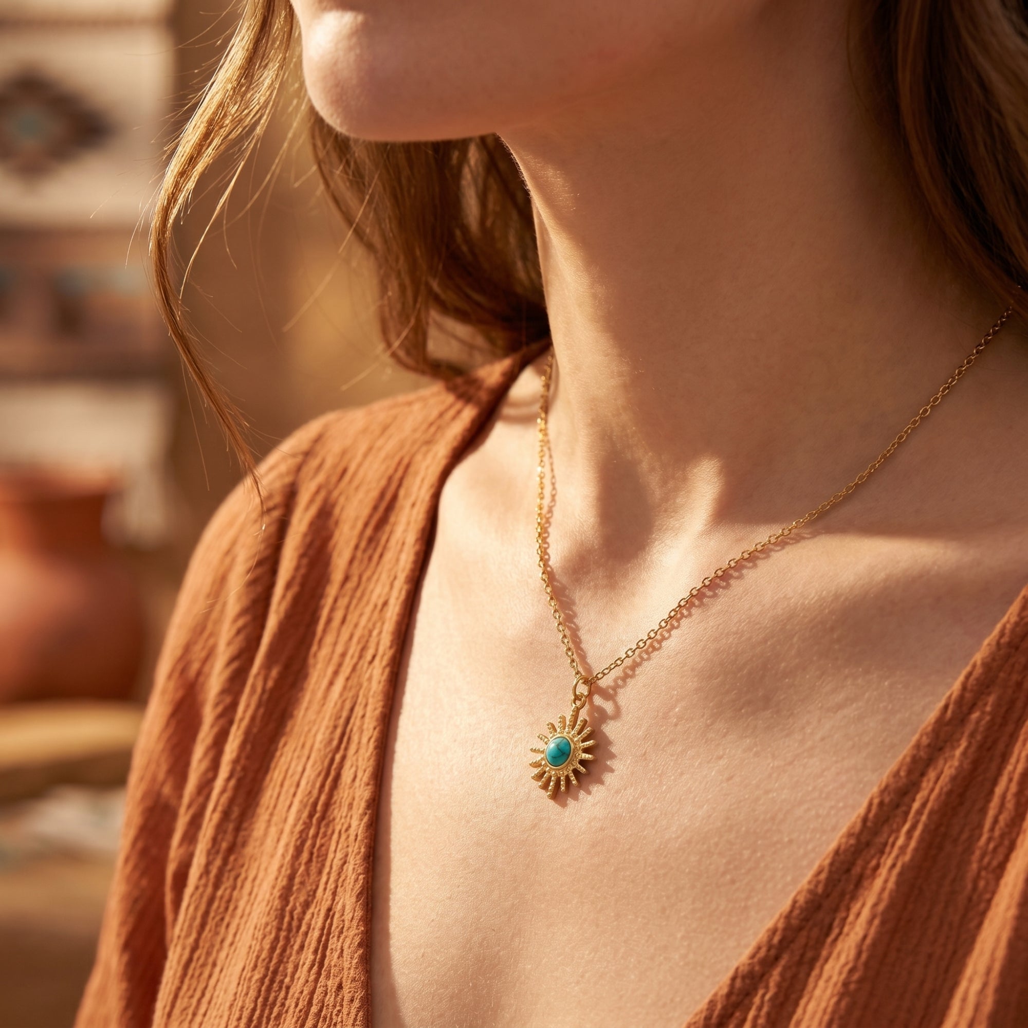 Model wearing the 18K gold sunburst turquoise necklace, styled with a terracotta top for a bohemian look.