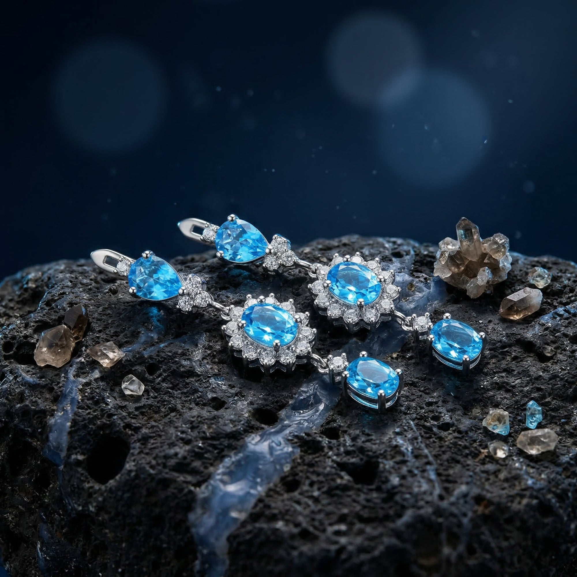 Close-up of silver drop earrings showing the precision-cut oval and pear Swiss blue topaz in halo settings.