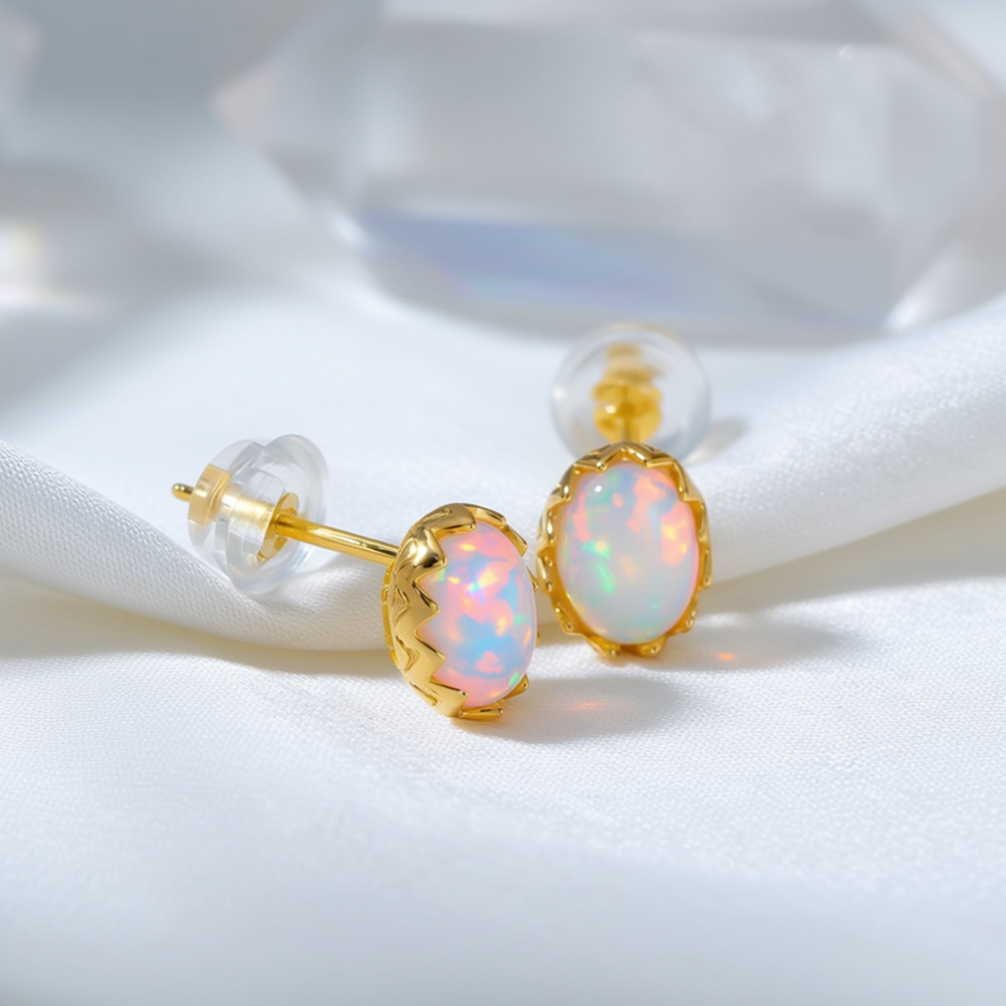 Close-up of yellow gold Novalie stud earrings showing the oval white opal settings and clear backings.