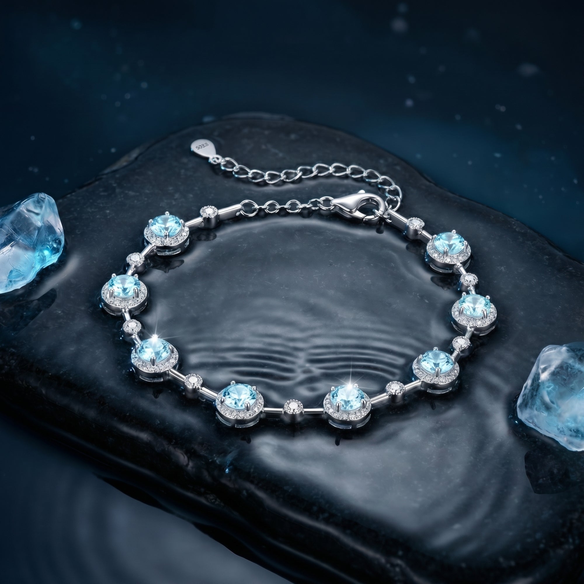 Overhead view of the round aquamarine sterling silver station bracelet on a rippled water surface.